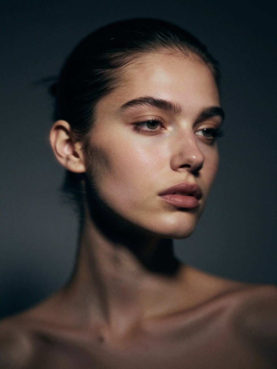 Z-Image Turbo generation: Ultra-close editorial portrait of a young woman in a dark studio, hair slicked back tightl…